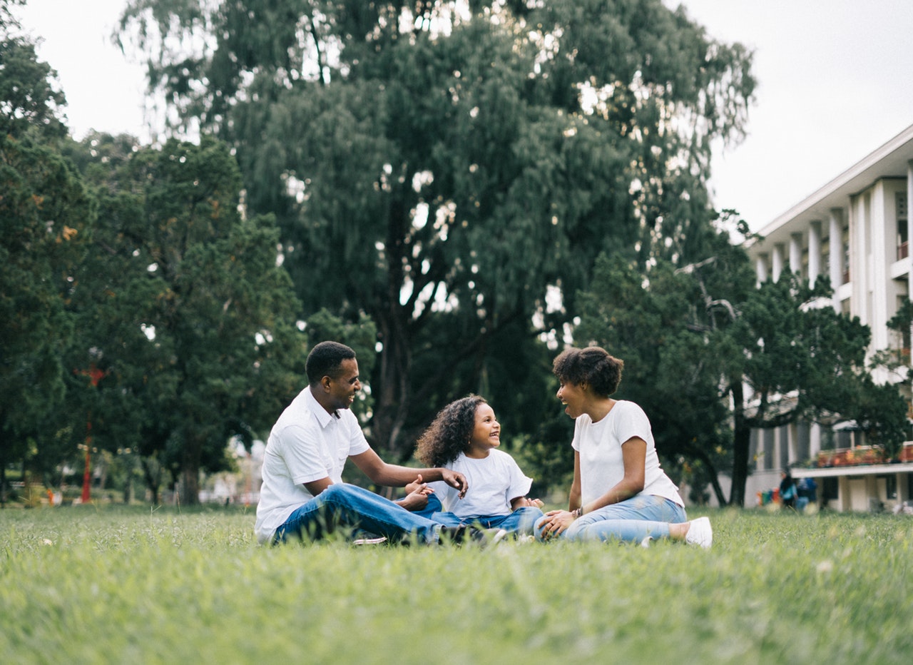 family-sitting-on-grass-near-building