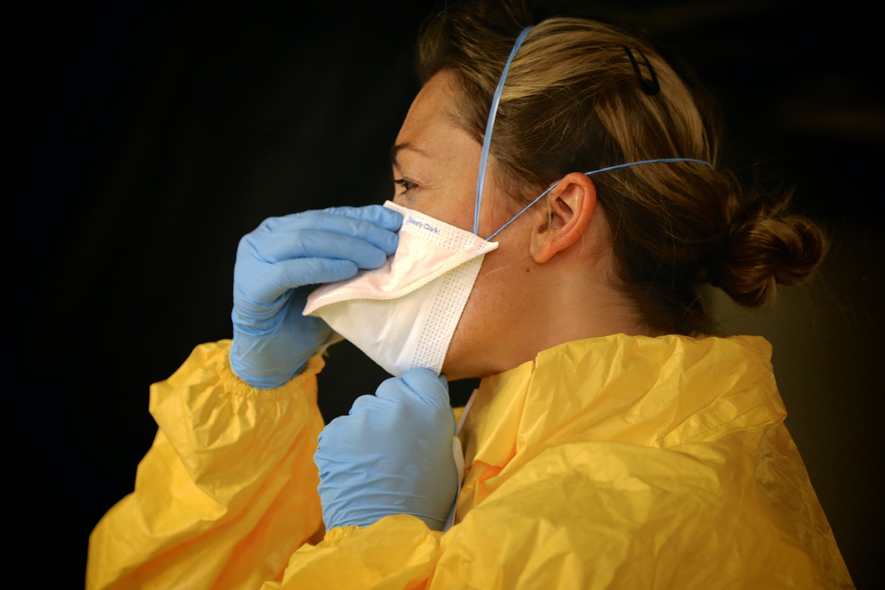 woman-in-yellow-protective-suit-wearing-white-face-mask