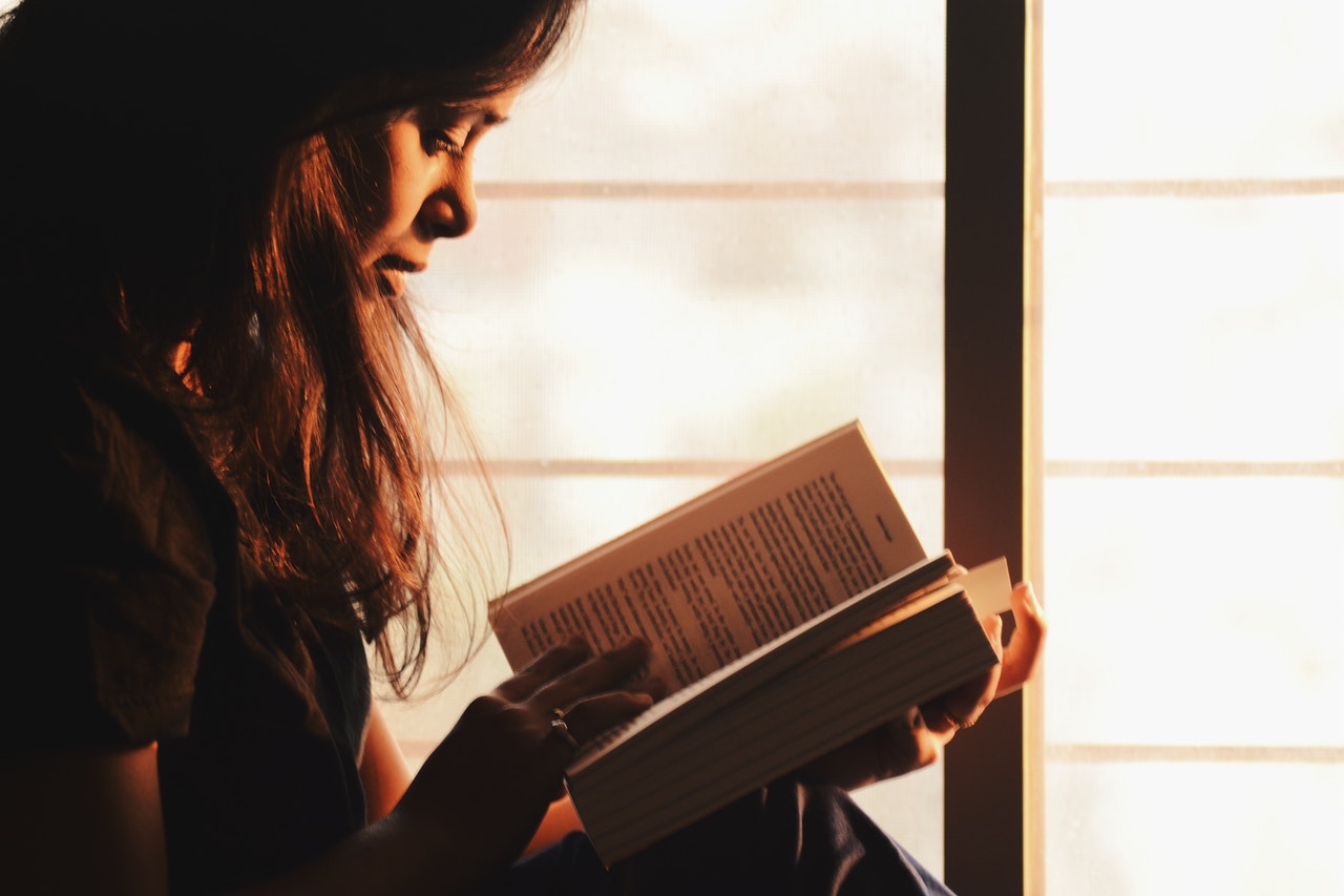 woman-reading-a-book-beside-the-window